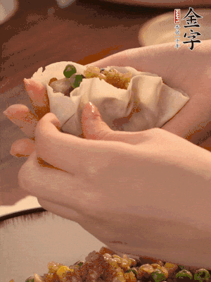 取一大勺餡料放進(jìn)餃子皮里，用大拇指按住頂部餡料，再用虎口掐出形狀。